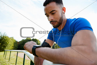 Male athlete at track checking smartwatch app, close up
