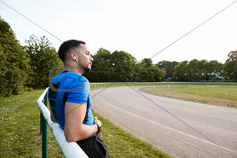 Male athlete wearing earphones taking a break at a track