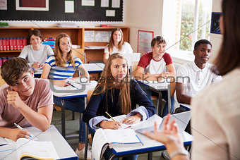 Students Listening To Female Teacher In Classroom