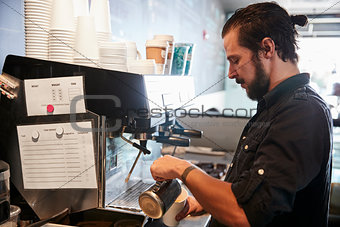 Male Barista Using Coffee Machine Behind Counter In Cafe