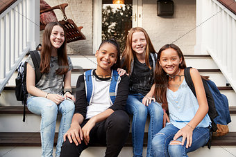 Young teen girls on front steps of house looking at camera