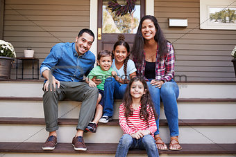 Portrait Of Family Sitting On Steps in Front Of House