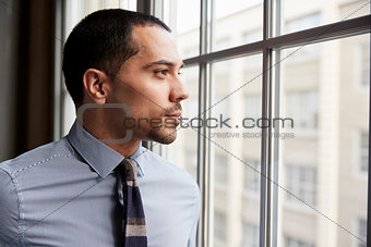 Young Hispanic business man looking out of window