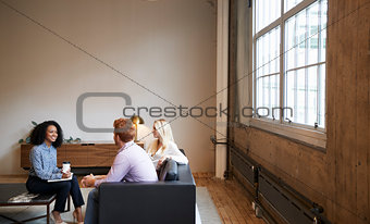 Three colleagues at a casual work meeting in a lounge area