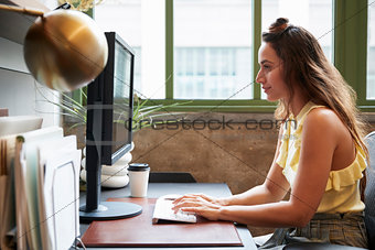 White woman working at a computer in an office, side view