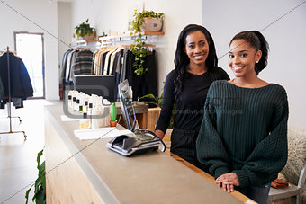 Two women smiling behind the counter in clothing store
