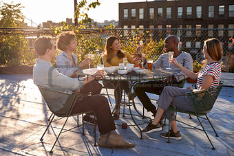Friends talking on a New York rooftop raise glasses
