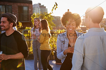 Happy friends at a rooftop party backlit by sunlight