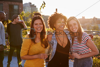 Female friends at a rooftop party smiling to camera