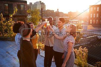 Friends make a toast at a rooftop party, backlit by sunlight