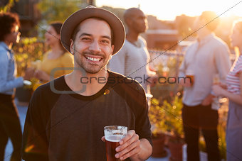Young man at a rooftop party smiling to camera