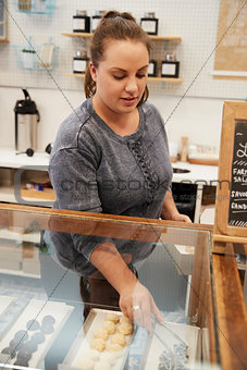 Young woman arranging the confectionary counter at a bakery