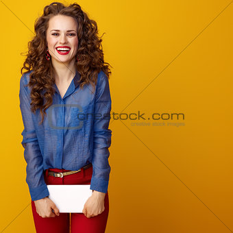 smiling modern woman on yellow background with tablet PC