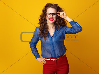 smiling trendy woman in glasses isolated on yellow background