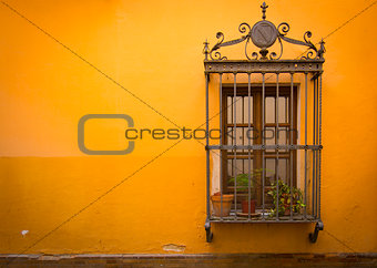 Antique medieval window with rusty iron bars and orangewall
