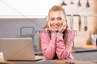 Young smiling woman sitting next to laptop