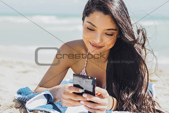 Pretty girl using phone on beach