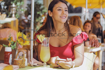 Smiling woman with smartphone in outside cafe
