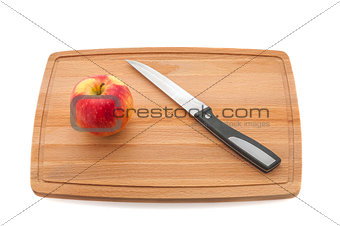 Red juicy apple and knife on a cutting board made of dark wood.