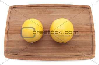 two yellow bright juicy lemon on a wooden cutting board top view
