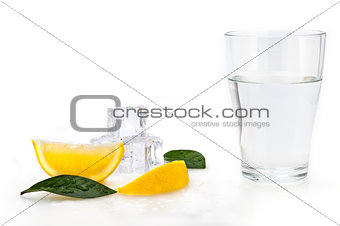 Water, lemon and ice cubes in a glass. Lemon slices and flax next to a glass.