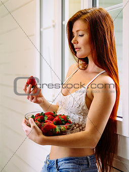 Beautiful redhead with bowl of strawberries