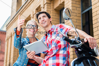 Couple on city trip planning their Vespa tour using tablet PC