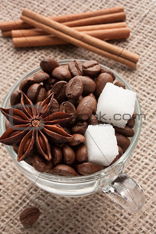 Coffee beans in glass cup with sugar and anise star.