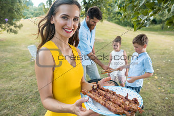 Portrait of mother holding plate with grilled steak skewers