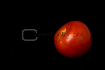 Red ripe tomato on a black background closeup