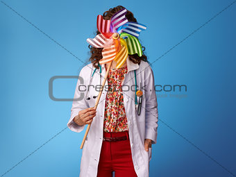 pediatrist woman holding colorful windmill in front of face