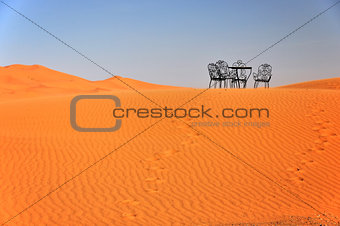 The chair and table stand on the top of the Erg Chebbi dune in Morocco.