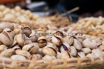Background of basket of pistachios without shells on market, selective focus