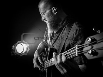 Bearded man playing bass guitar on stage