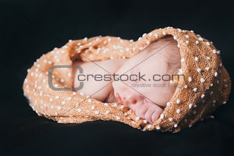 newborn baby lying on a black background. Imitation of a baby in the womb. beautiful little girl sleeping lying on her tummy.