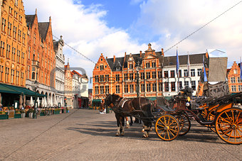 Old houses and horse carriages on Grote Markt square, Brugge, Be