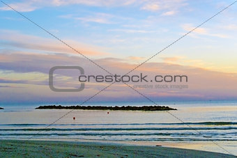 The outfall on sand beach. Beautiful sunrise sky over sea