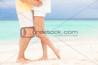 legs of young hugging couple in love on tropical turquoise beach