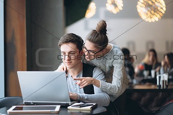 Beautiful couple watching on the laptop in the cafe.