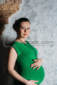 Portrait of pregnant woman in long dress on white background