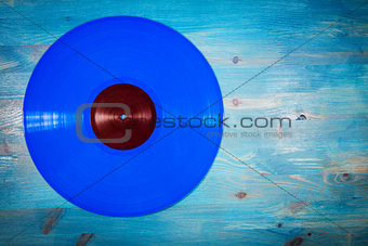 Blue color vinyl record on blue wooden background
