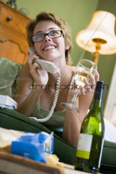 Woman at home on phone drinking wine